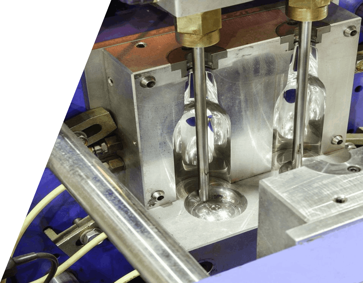 Close-up of a plastic injection molding machine with two cavities, showing metal molds and plunger rods for shaping plastic parts.