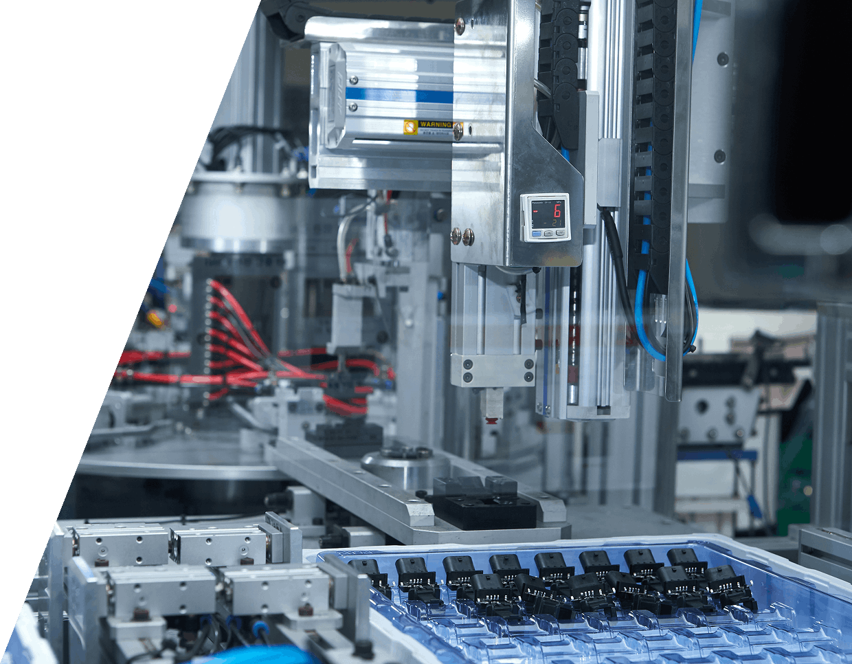 jpeg-optimizer_GettyImages-1371069614 (2) Robotic machinery assembling electronic components in a factory setting, with conveyor and organized components in trays.
