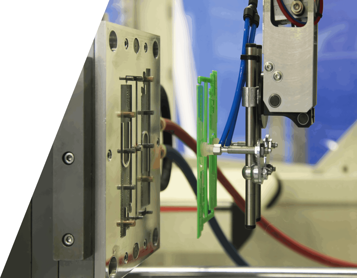 jpeg-optimizer_GettyImages-1371069614 (4) A robotic arm operates on an injection molding machine, holding a green plastic part in a factory setting.