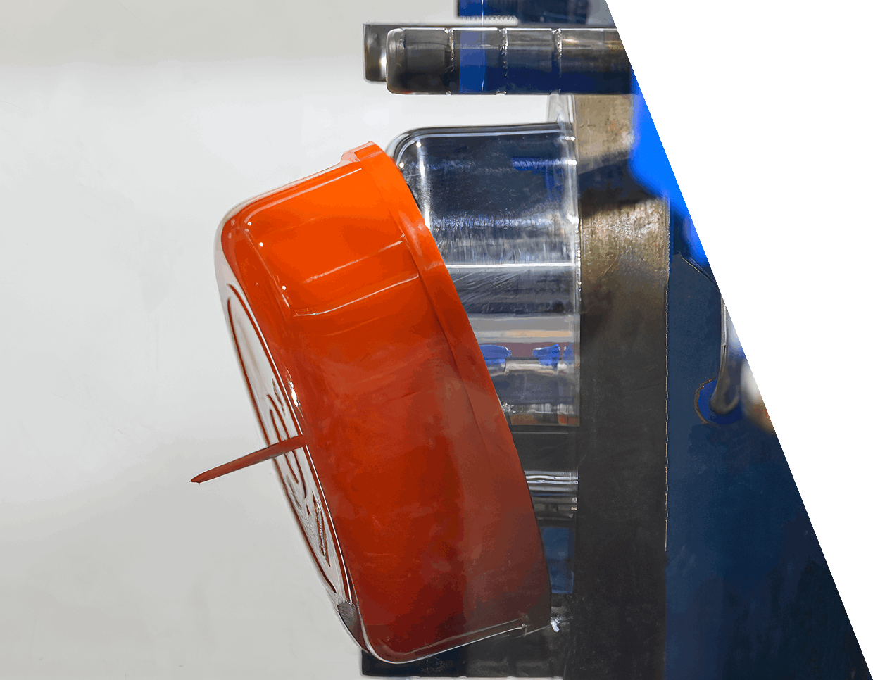 jpeg-optimizer_GettyImages-1407133291 (1) Close-up of an orange plastic object with a small protruding pin, positioned on a metallic apparatus, possibly part of an industrial or manufacturing process.