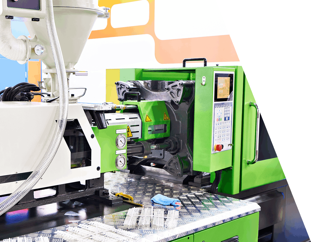 jpeg-optimizer_GettyImages-1407133291 (3) Green and white plastic injection molding machine on a factory floor, featuring control panel and safety warnings.