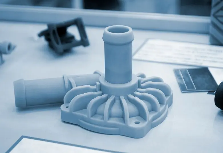 jpeg-optimizer_GettyImages-1805459412 A blue-toned, industrial plastic component with a cylindrical shape and ribbed base is displayed on a table among other mechanical parts.